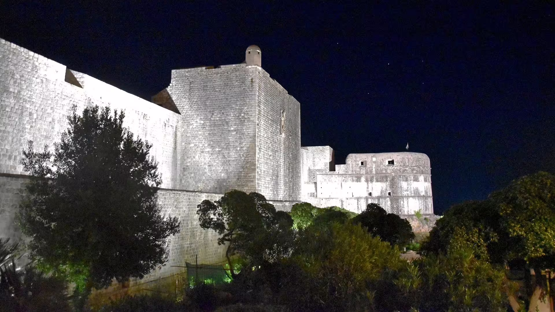 Dubrovnik Old Town city walls lit at night, scenic evening group tour stop with dramatic fortress views