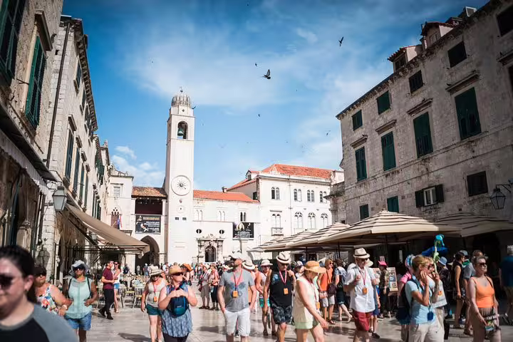 Crowded Dubrovnik Old Town Stradun street with clock tower, ideal for Old Town and City Walls combo tour