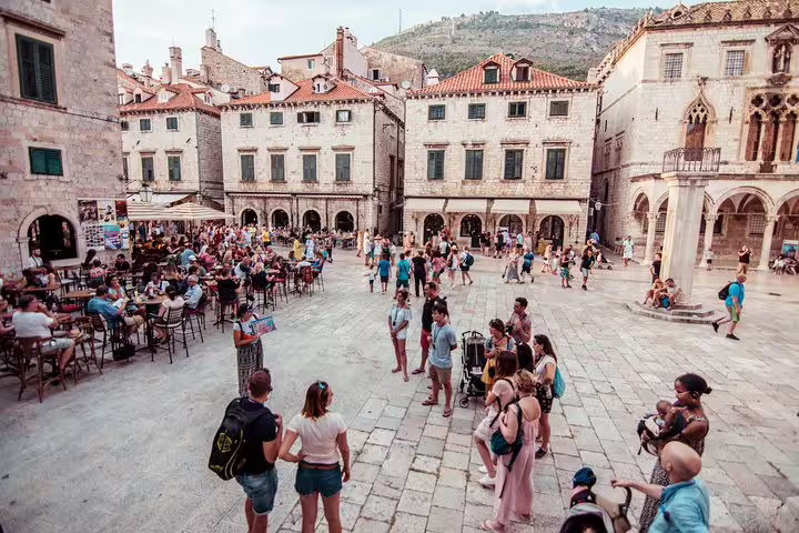 Dubrovnik Old Town guided walking tour in Stradun square, historic cafes and stone buildings bustling with visitors