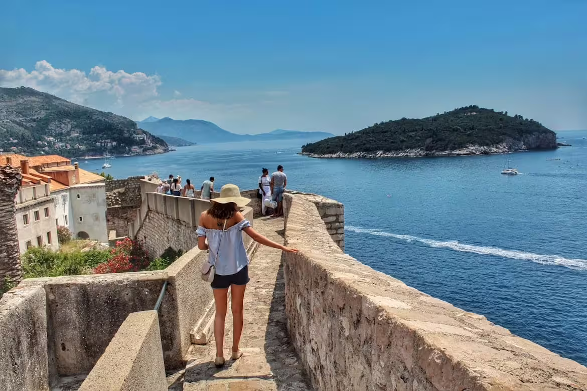 Traveler walking Dubrovnik Old Town city walls with Adriatic Sea views on a guided group tour in Croatia