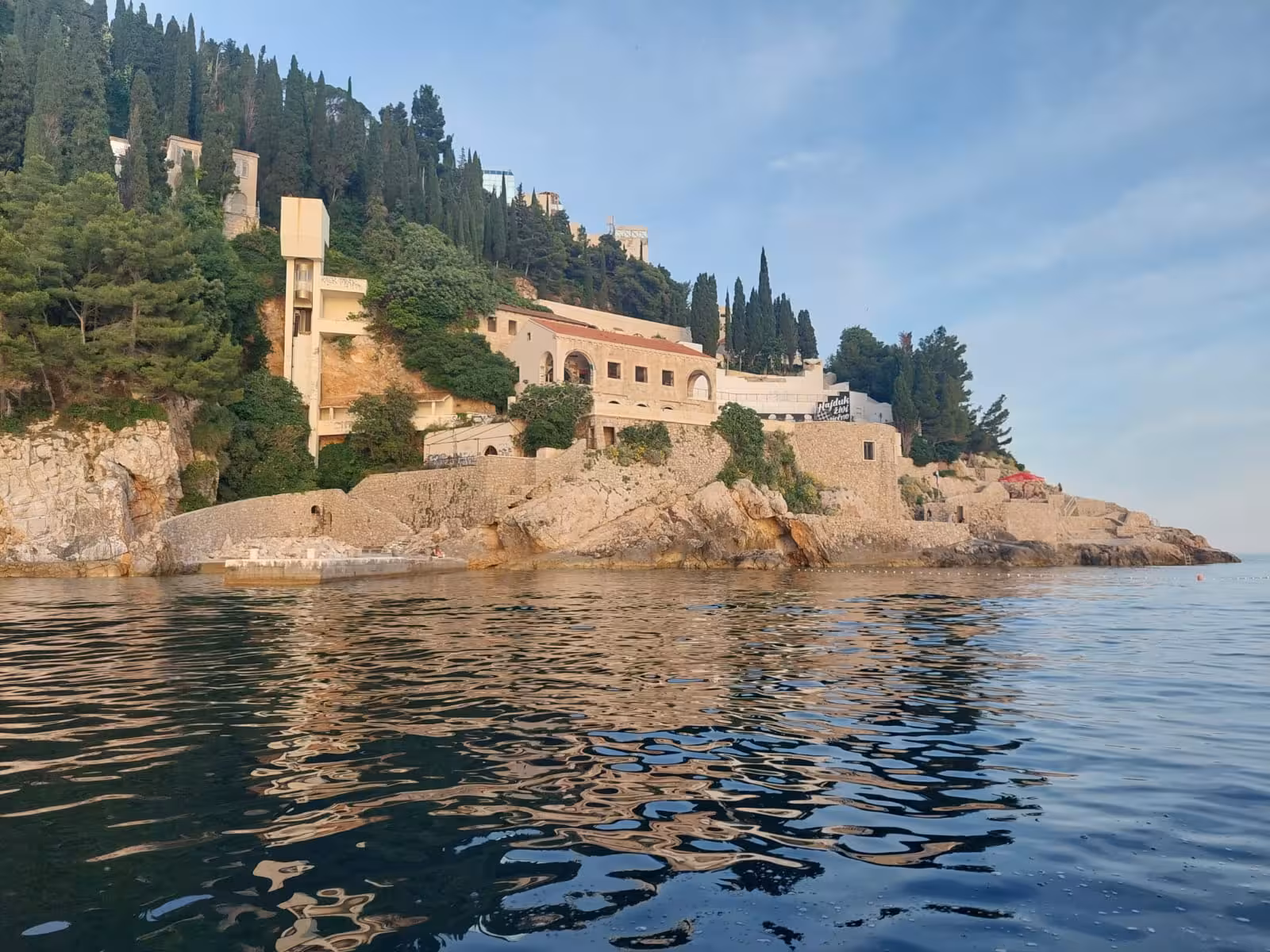 Boat view of Dubrovnik coastline at golden hour, scenic Adriatic cruise on sunset by boat tour