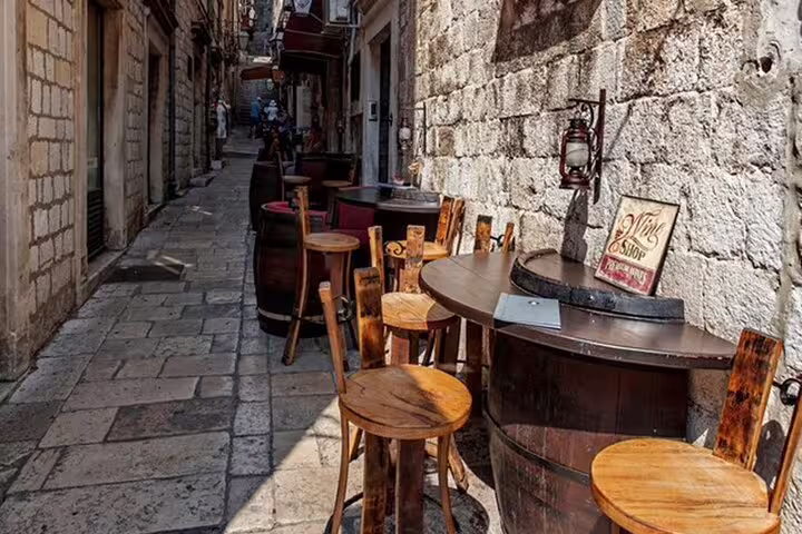 Rustic wine bar tables in a Dubrovnik Old Town alley, perfect for local Croatian wine tasting on the tour