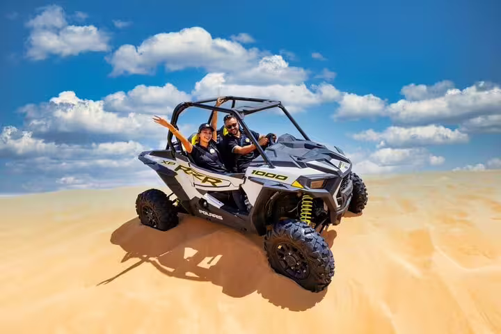 Thrilling dune buggy adventure in Dubai's desert with blue skies and golden sands, perfect for quad bike rentals and tours.