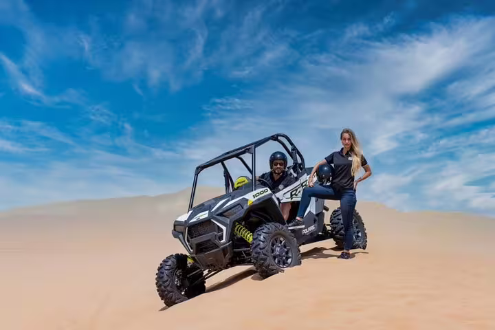 Adventurers enjoying a thrilling dune buggy ride in Dubai's desert landscape under a clear blue sky, ideal for off-road enthusiasts.