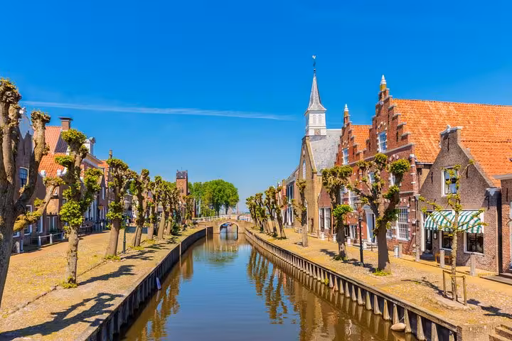 Historic canal street in Dutch village with gabled houses and church, on Discover The Netherlands tour from Amsterdam