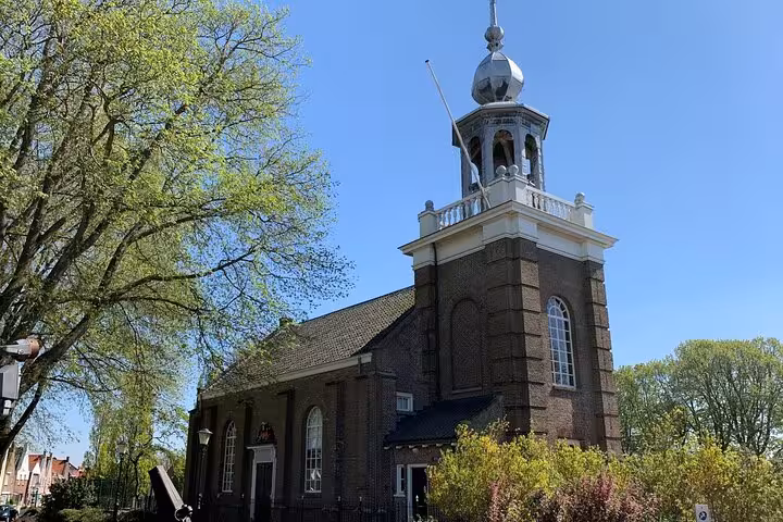 Traditional Dutch church with bell tower and spring trees, Discover The Netherlands tour from Amsterdam