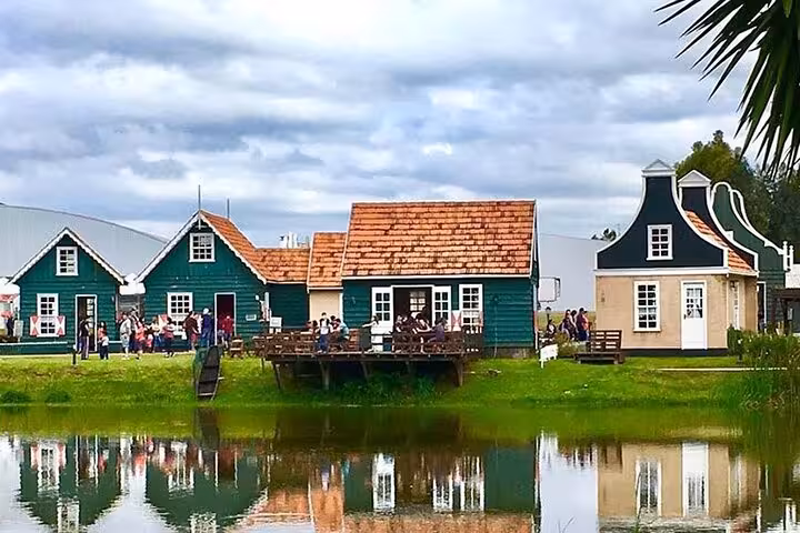 Charming Dutch colonial houses reflect in a tranquil pond on an 8-hour guided tour of Paraná's Dutch heritage.