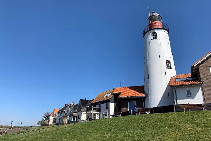 Coastal Dutch lighthouse above a dike and seaside homes, Discover The Netherlands day tour from Amsterdam