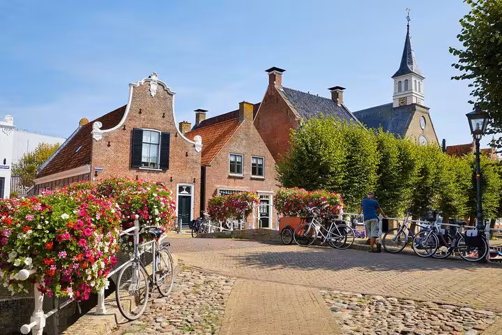 Historic Dutch village square with canal bridge flowers and bikes, Discover The Netherlands tour from Amsterdam