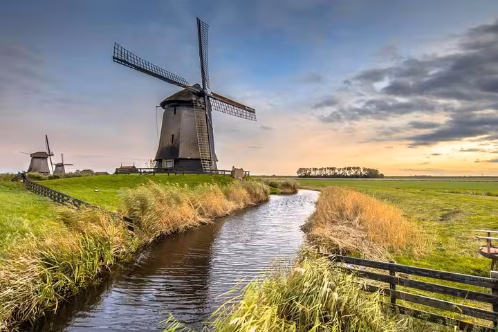 Historic Dutch windmill by a canal at sunset, iconic stop on Best of Dutch Legacy private tour from The Hague