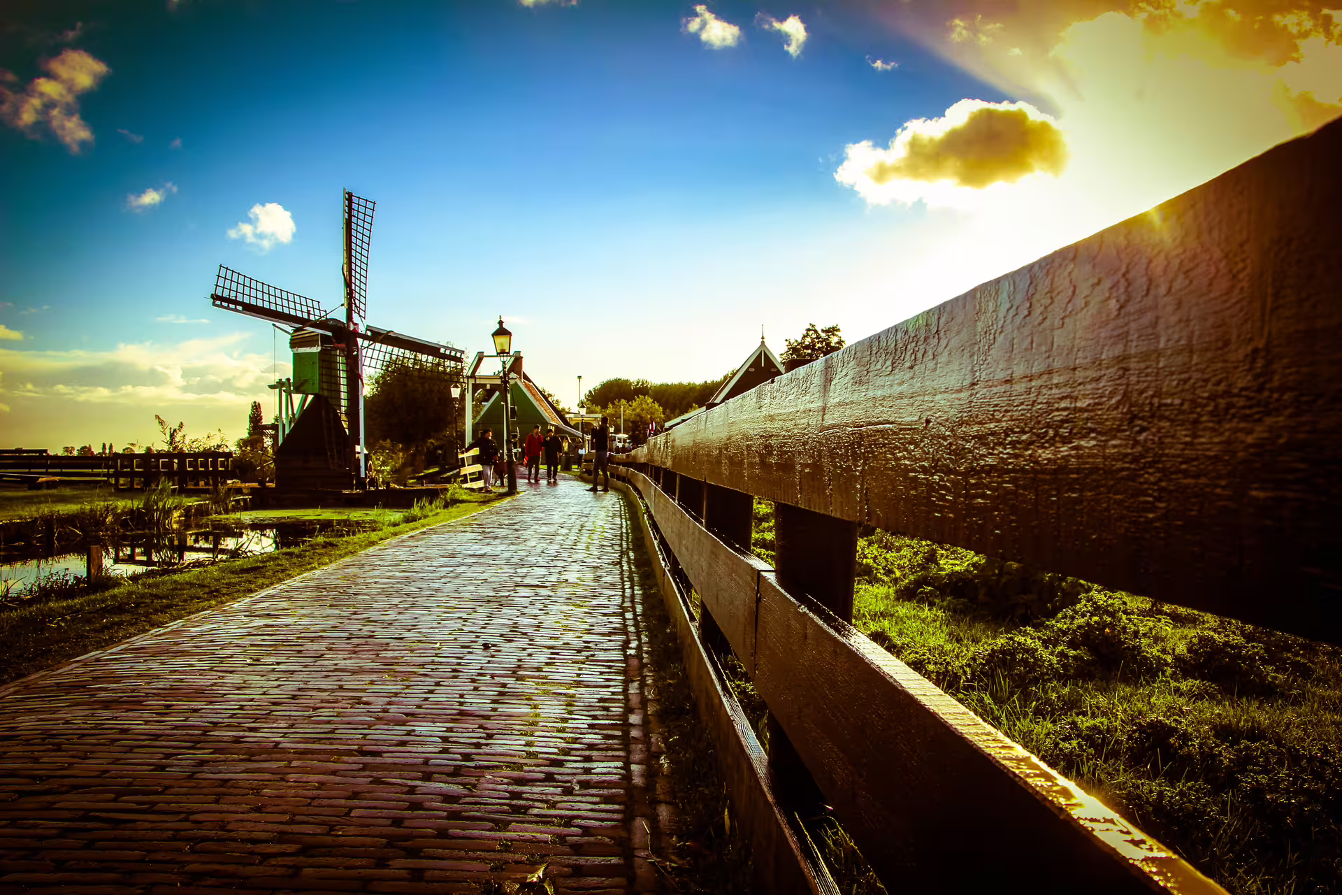 Scenic view of a traditional Dutch windmill and cobblestone path at Zaanse Schans during sunset, perfect for exploring historic villages.