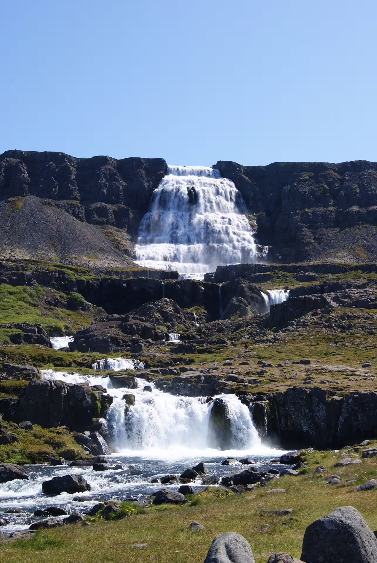 Dynjandi waterfall cascading down rocky cliffs in Iceland's Westfjords on a sunny day