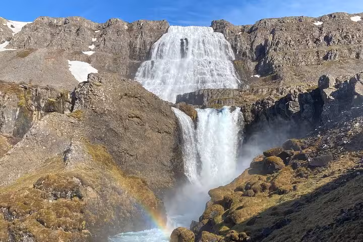 Dynjandi waterfall cascading down rocky cliffs with rainbow mist in Iceland's Westfjords