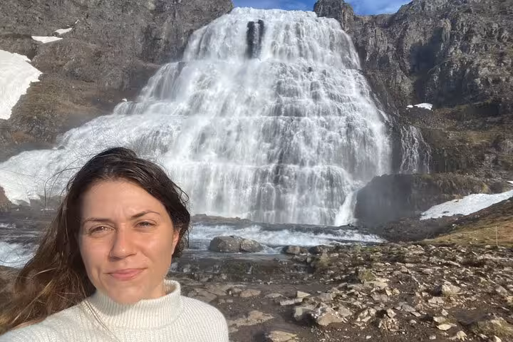 Woman smiling in front of Dynjandi waterfall in the Westfjords of Iceland