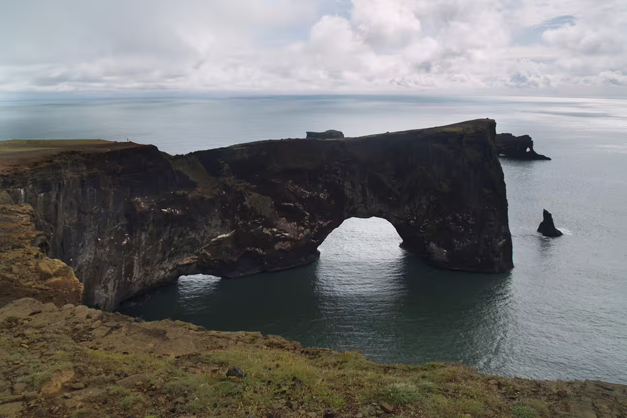 Dramatic black rock arch at Dyrhólaey cape on Iceland's south coast with calm ocean views