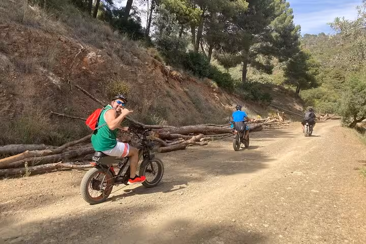 Riders on e-fat bikes tackling a forest dirt trail near Málaga on a 10-hour self-guided rental adventure