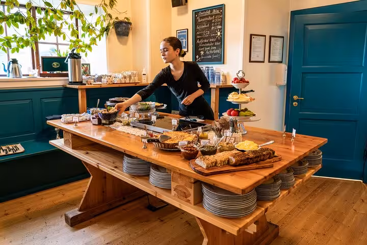 Staff arranging buffet spread on large wooden table in cozy East Iceland dining room