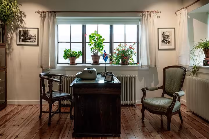 Vintage wooden desk with typewriter and Icelandic flag in a cozy East Iceland office with plants