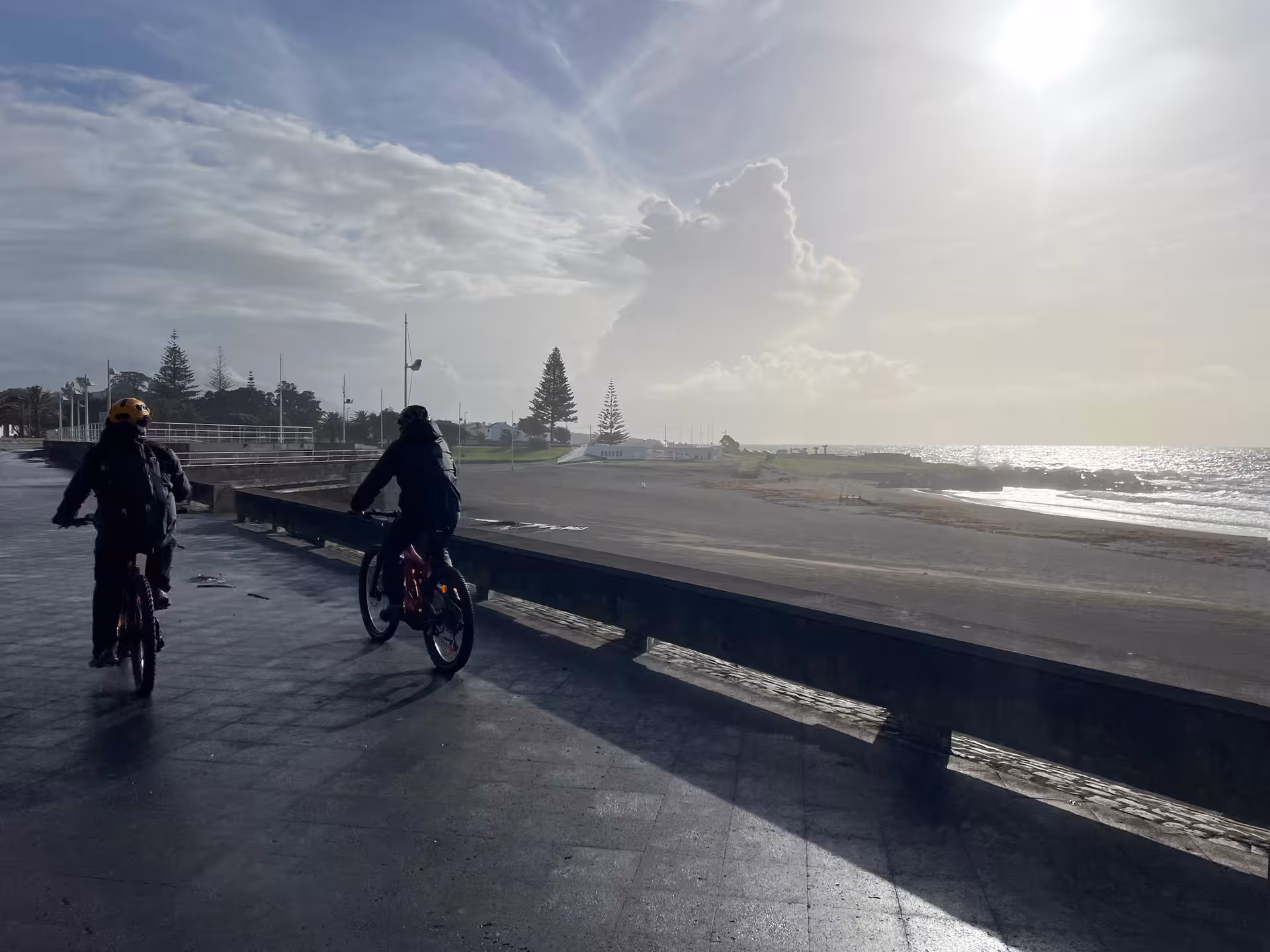 Small group e-bike tour riding along the Ponta Delgada oceanfront promenade at sunrise with Atlantic coastal views
