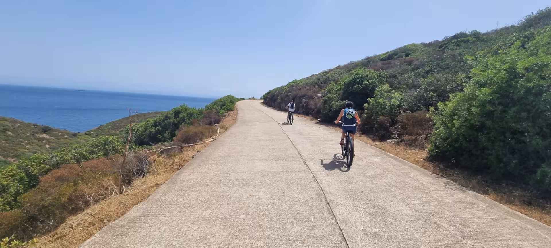 Cyclists enjoy scenic e-bike ride along Asinara coastline from Porto Torres under sunny skies.
