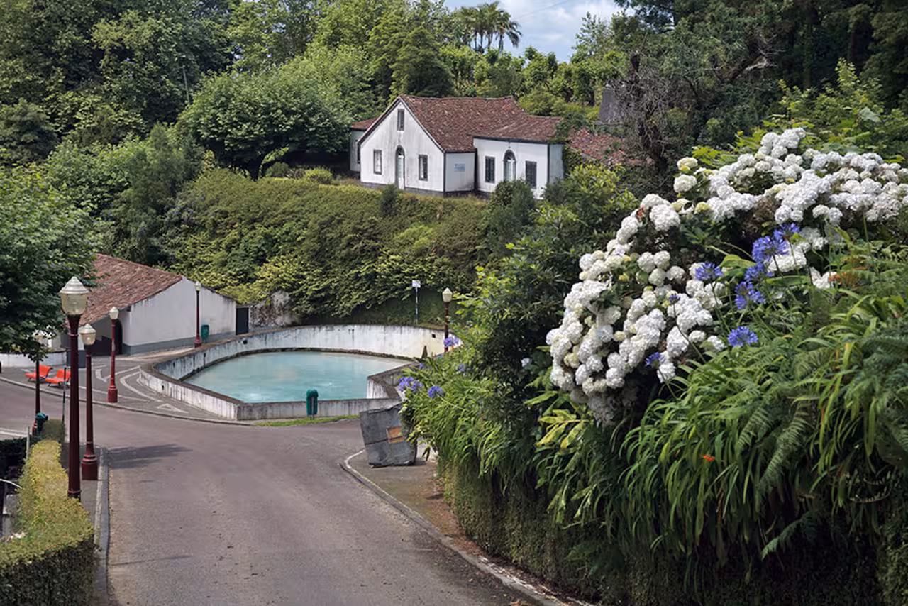 Scenic Ribeira Grande e-bike route passing a tranquil pool, historic white house and lush hydrangeas in São Miguel, Azores
