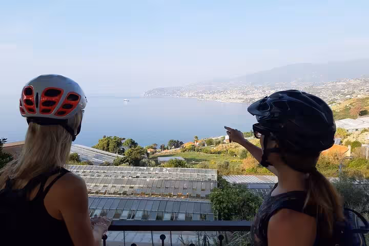 Two cyclists admire the scenic Ligurian coastline view during a small group E-bike tour.