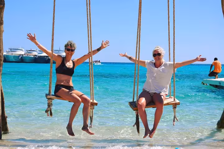 Friends on seaside swings at Eden Island, Red Sea day trip from Hurghada with water sports and lunch