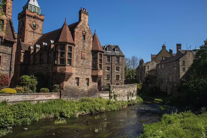 Historic Dean Village in Edinburgh with picturesque stone buildings and a tranquil stream, featured on the Edinburgh Express tour.