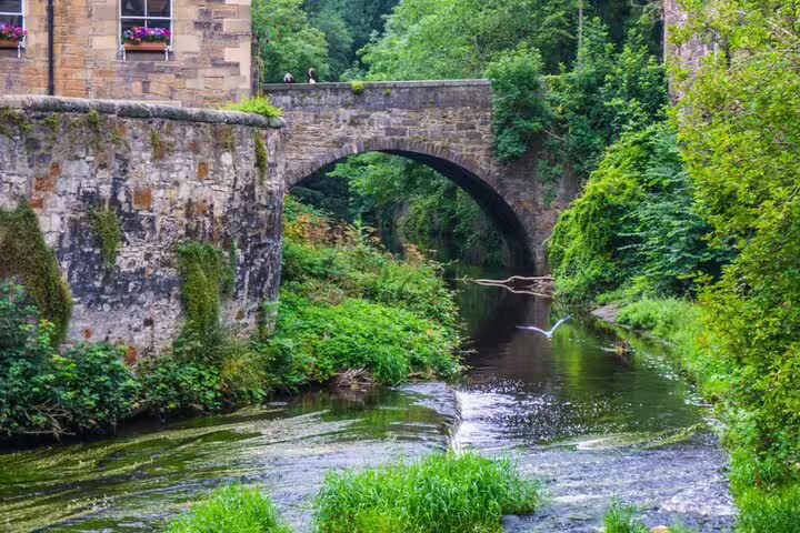 Stone arch bridge over a lush green river in Edinburgh, Scotland