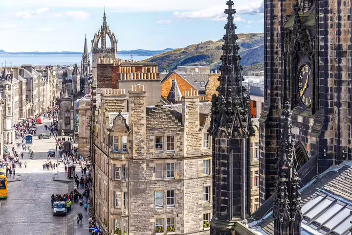 Aerial view of Edinburgh's Royal Mile with Gothic spires, medieval stone buildings, and crowds of tourists below