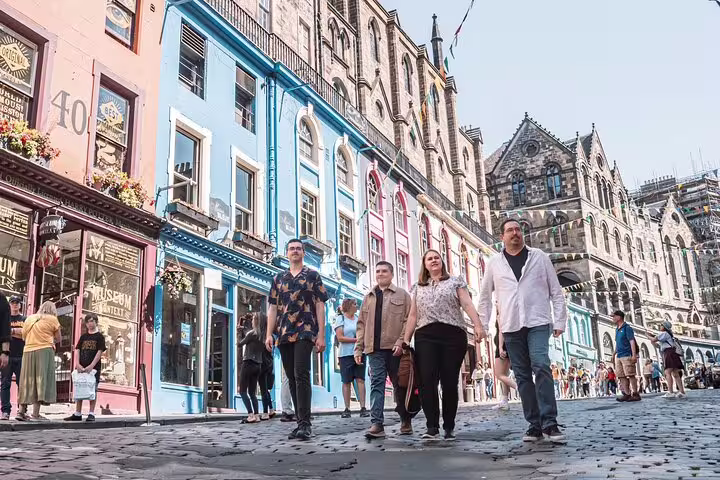 Group walking on Edinburgh Royal Mile during private photoshoot, colorful Old Town buildings and skyline behind