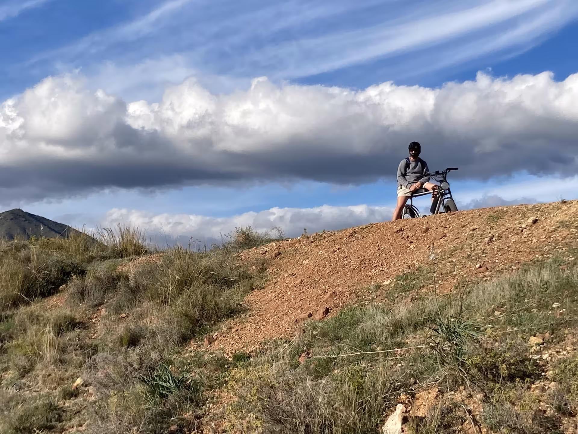 Rider on e-fat bike rental atop rugged trail viewpoint, perfect for a 4-hour off-road coastal adventure