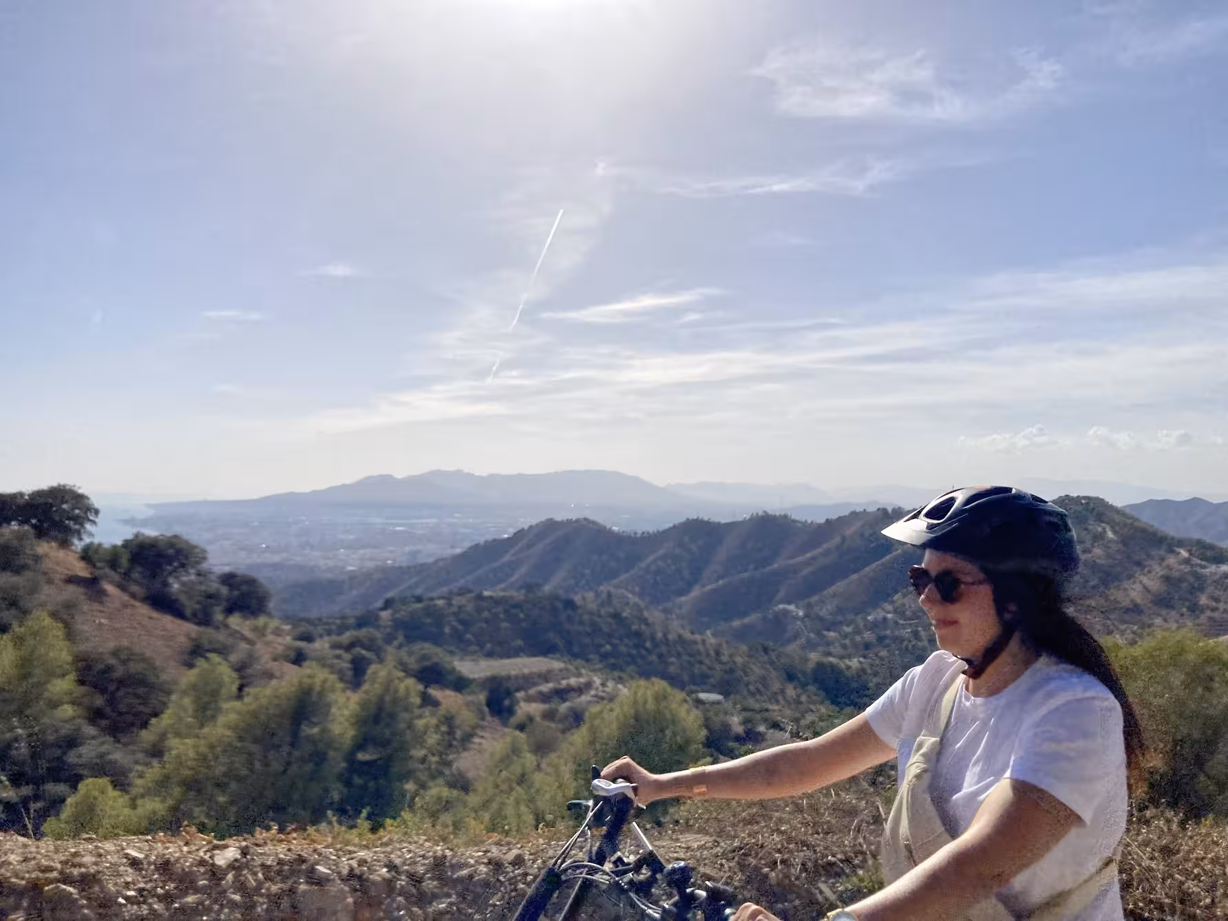 Helmeted rider on an e-fat bike enjoying mountain trails and distant coastline views during a 4-hour rental