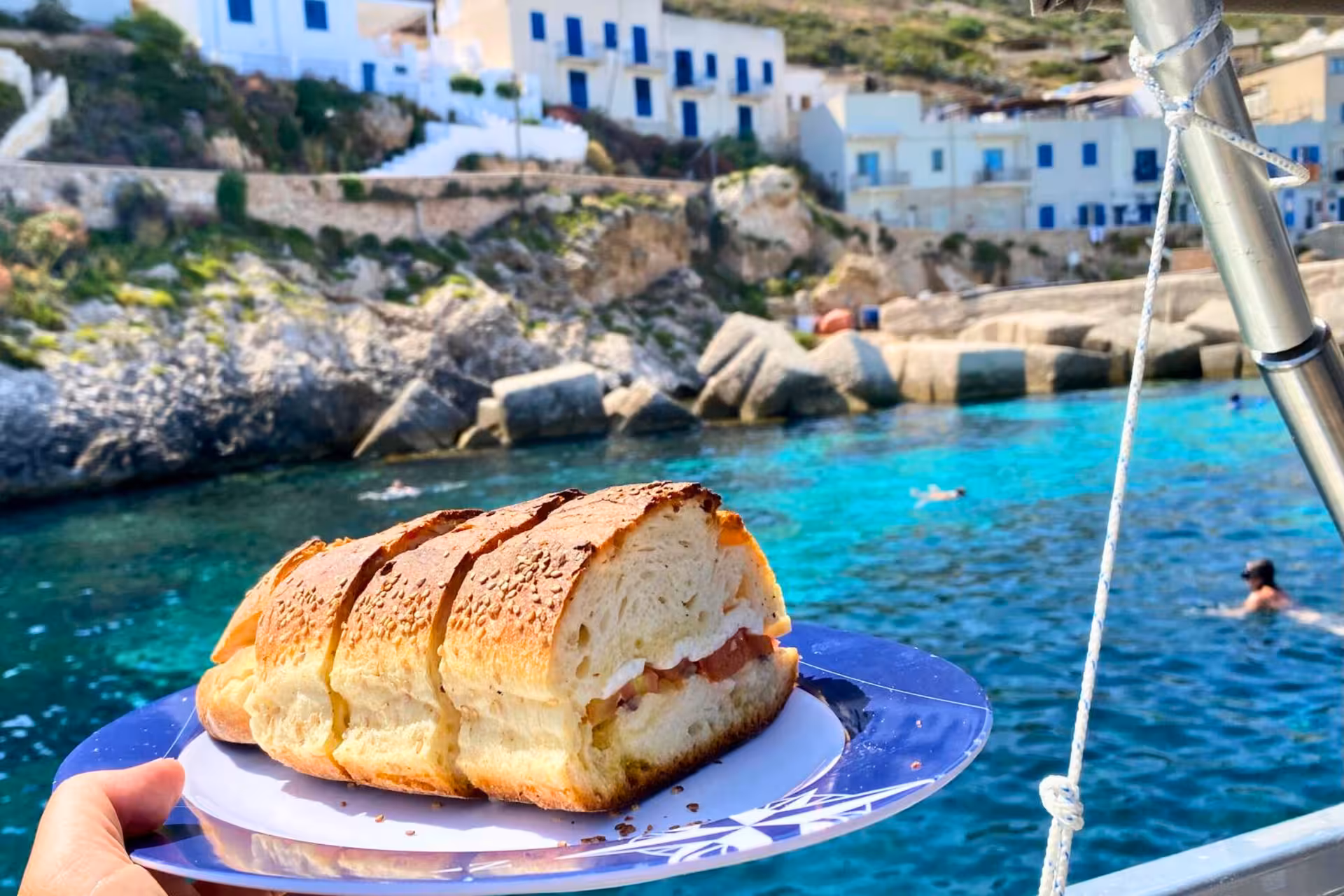Boat tour lunch sandwich served onboard in turquoise cove at Favignana, Egadi Islands excursion from Trapani