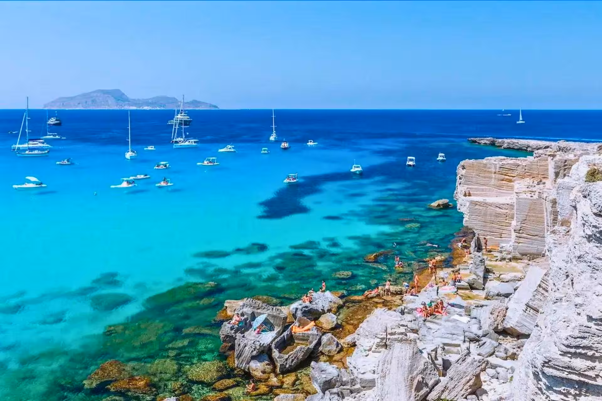 Turquoise Cala Rossa in Favignana with boats anchored, scenic stop on Egadi Islands boat tour from Trapani