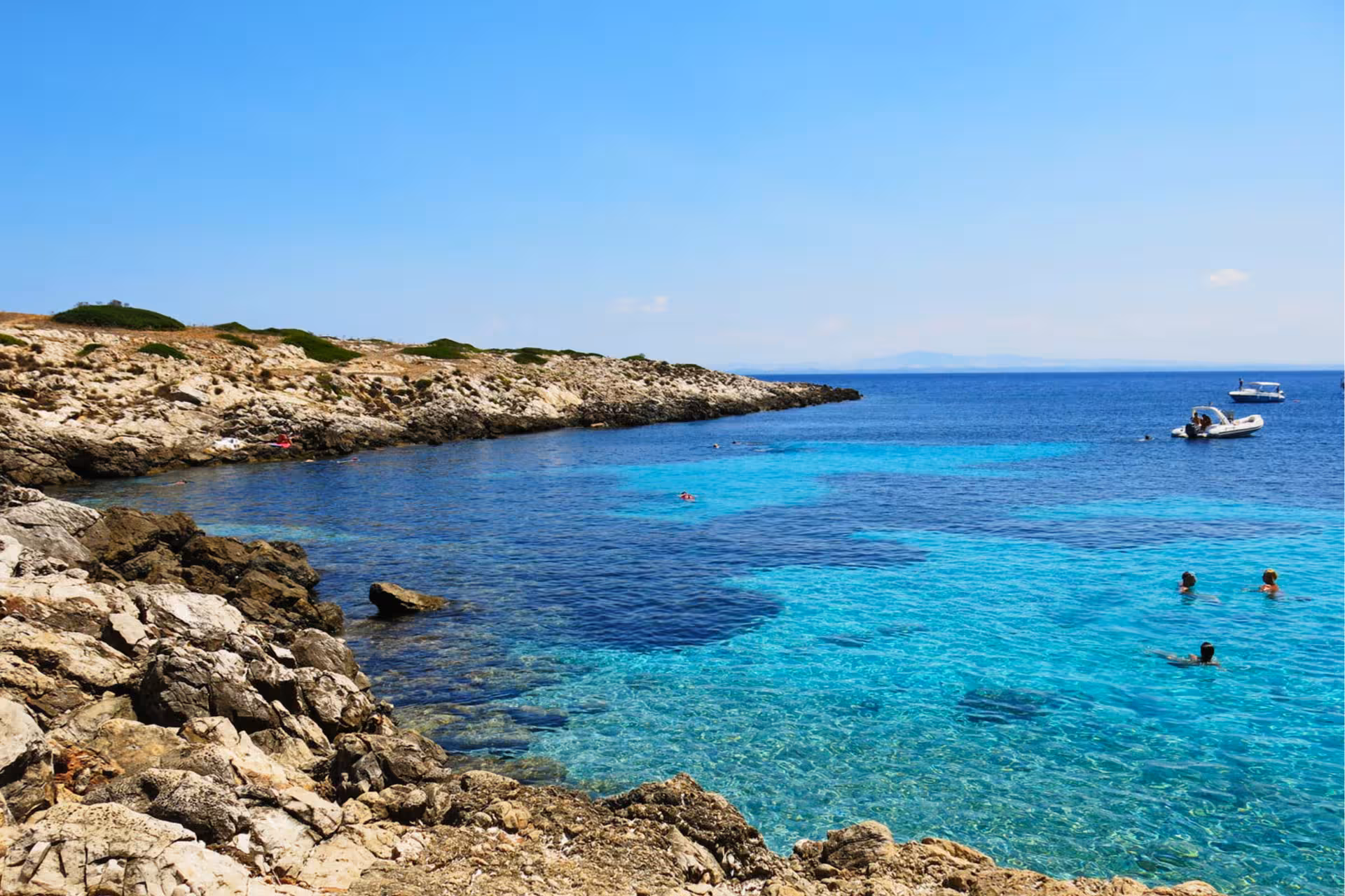 Turquoise cove in Favignana on an Egadi Islands private dinghy tour from Trapani, with swimmers and boats