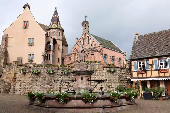 Historic fountain and pink chapel in Eguisheim village square, Alsace, France