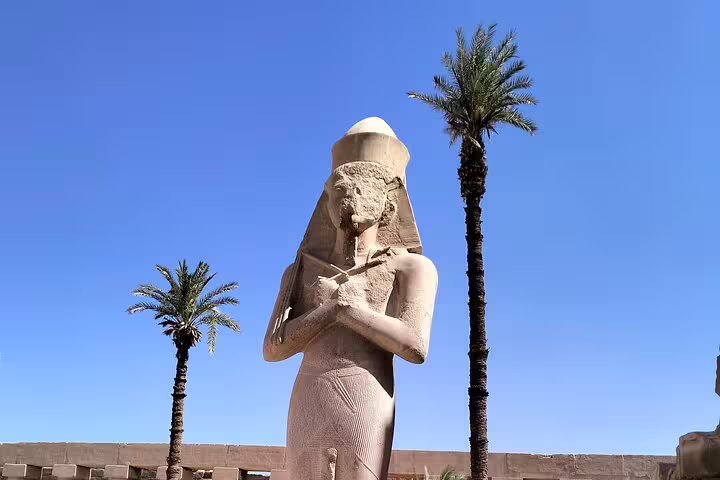 Ancient Egyptian pharaoh statue at Luxor Temple with palm trees, Cairo pyramids Nile cruise Hurghada