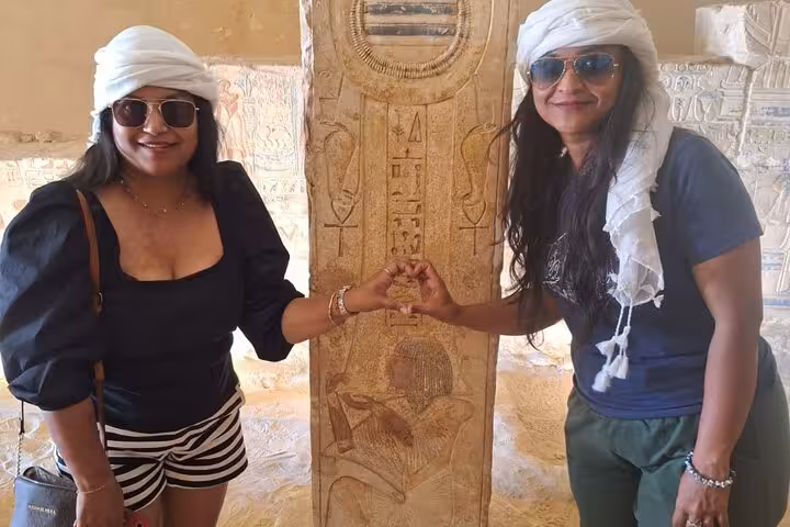 Two tourists posing with ancient Egyptian hieroglyphs in a temple, part of the unique 11-day Egypt tour with Nile cruise.