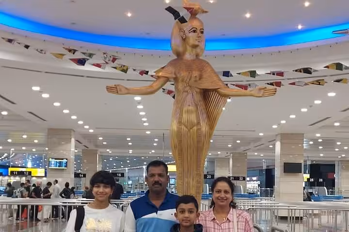 Travelers at an airport with a Pharaoh statue, marking the start of a unique 11-day all-inclusive Egypt tour.