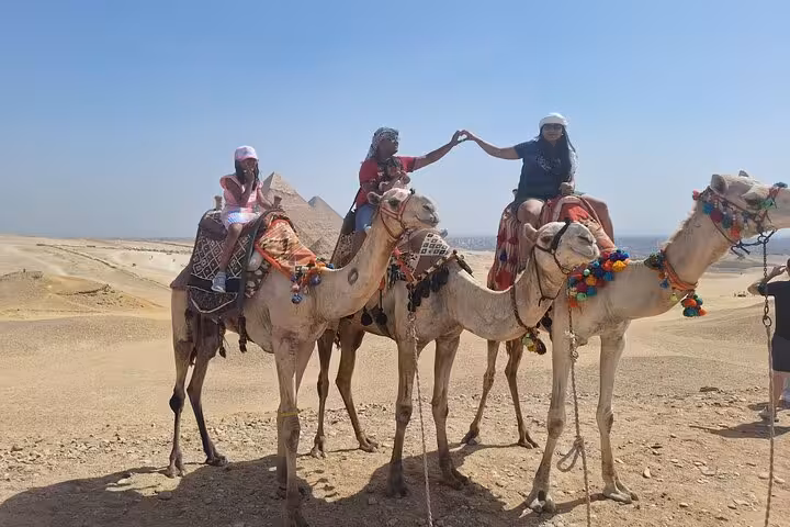 Tourists experiencing a camel ride by the Pyramids, showcasing the adventure of a unique Egypt tour.