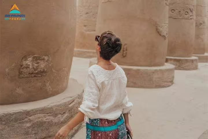 Traveler admiring ancient temple columns in Luxor on 15-day Egypt tour to Pyramids, Aswan and oases