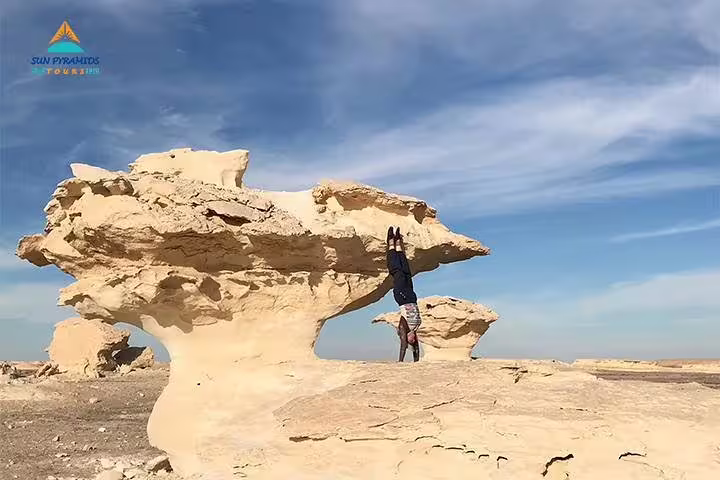 Traveler posing by White Desert mushroom rock in Egypt oasis safari, part of 15 days Pyramids Luxor Aswan package