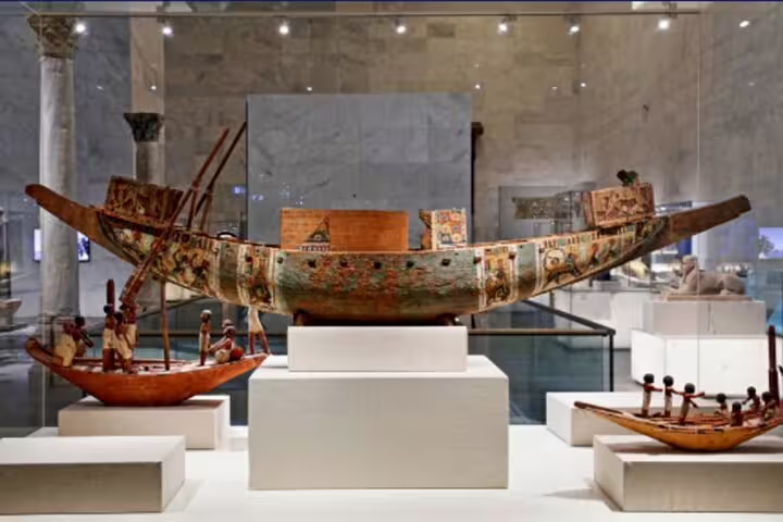 Painted ancient Egyptian funerary boat model on display at Cairo museum, featured in Egyptian Museum and NMEC tour