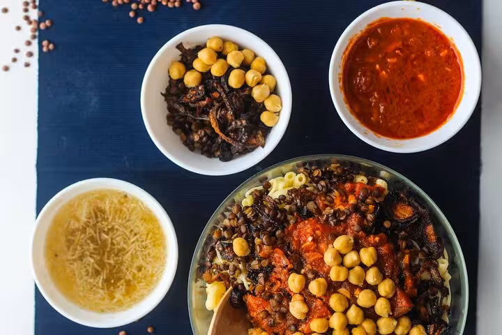 Traditional Egyptian koshari dish with chickpeas, lentils, and tomato sauce, perfect for an authentic Cairo food tour.