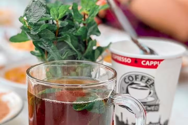 Glass of Egyptian mint tea beside coffee cup on a farm breakfast table, Green Farm Egypt tour experience