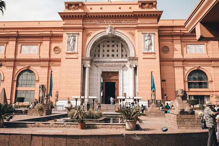 Egyptian Museum Cairo main entrance on a Cairo day tour, with statues, flags and visitors outside
