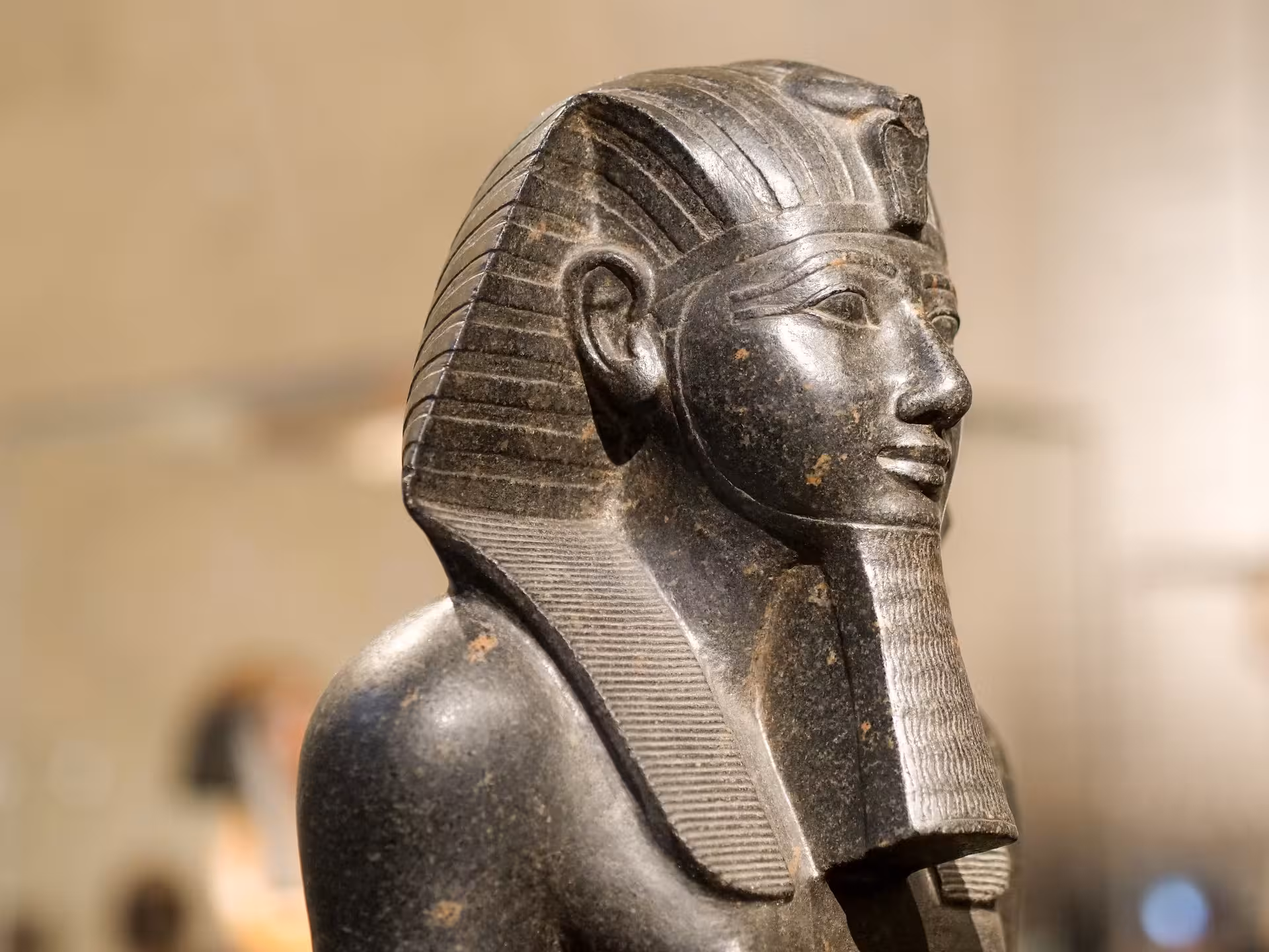 Dark granite ancient Egyptian pharaoh statue with nemes headdress and false beard at Grand Egyptian Museum