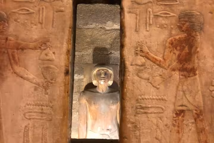 Ancient Egyptian statue framed by carved temple doorway, Memphis and Saqqara private tour from Giza