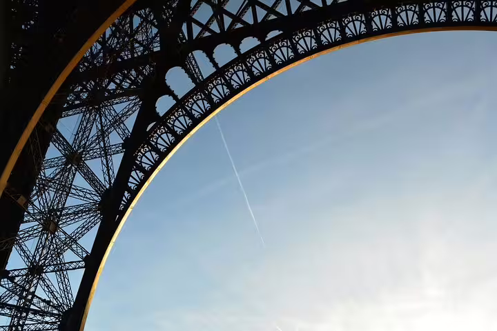 Close-up view of Eiffel Tower iron arch with decorative latticework against blue sky